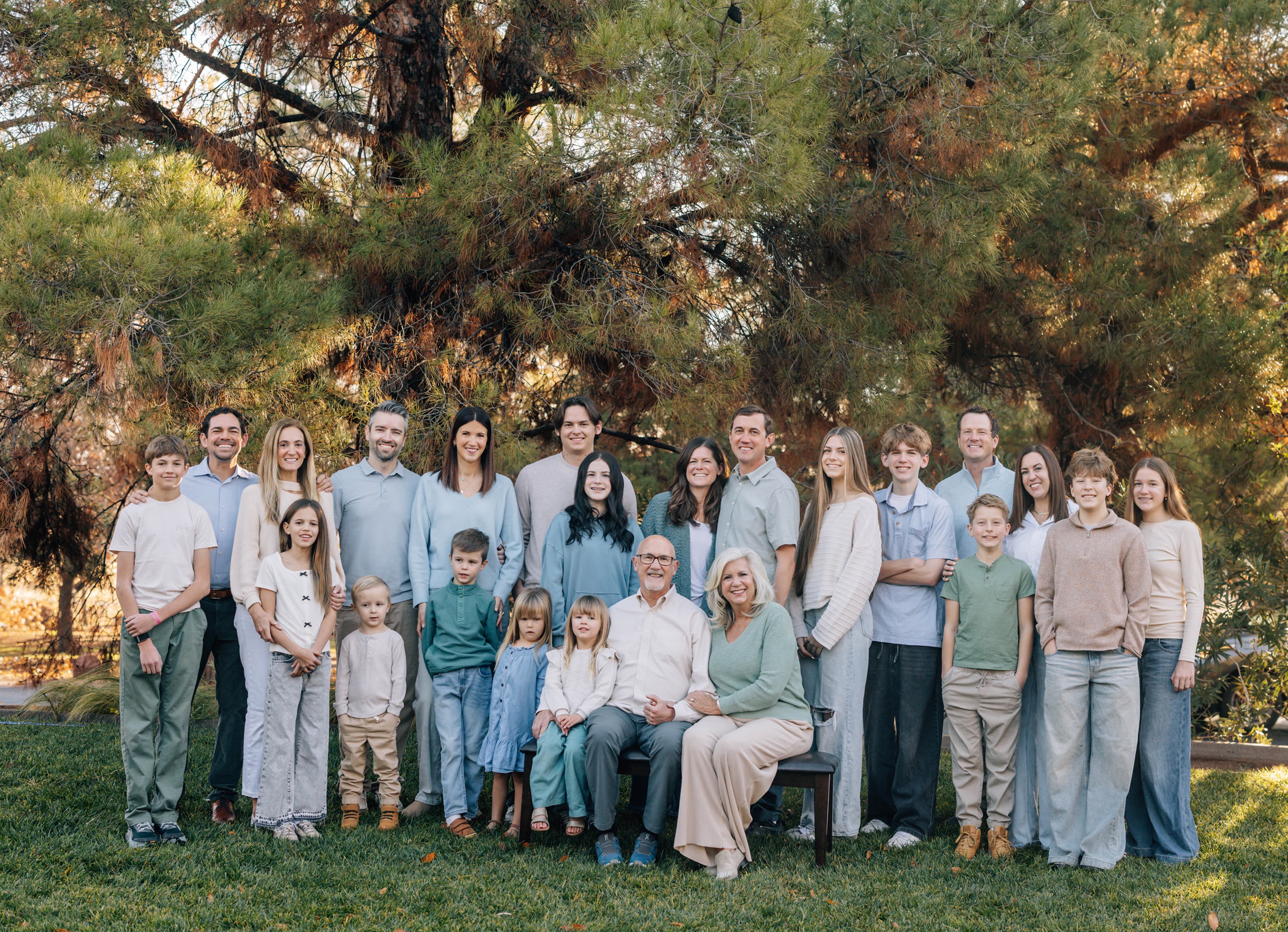 Celeste Johnson with her extended family outdoors, multi-generational portrait in front of a large pine tree